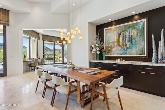 dining space featuring a towering ceiling, light tile patterned floors, and an inviting chandelier