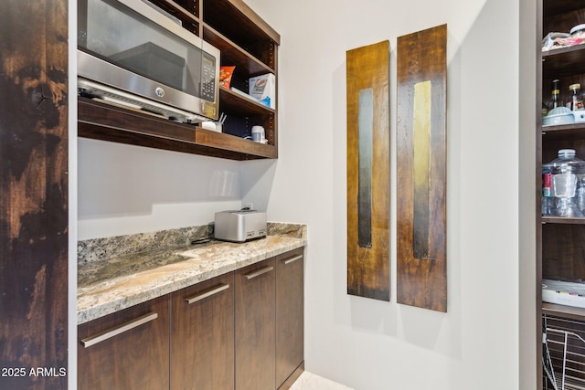 bar featuring light stone counters and dark brown cabinetry