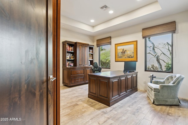 office space featuring a raised ceiling and light wood-type flooring