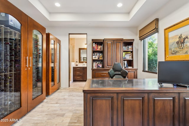 office space with french doors, a raised ceiling, and light wood-type flooring