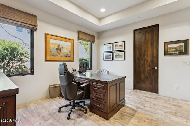 office area featuring a tray ceiling and light wood-type flooring