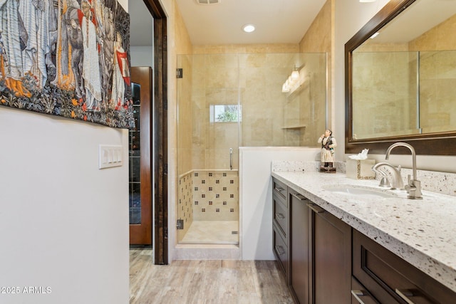 bathroom with a shower with door, wood-type flooring, and vanity