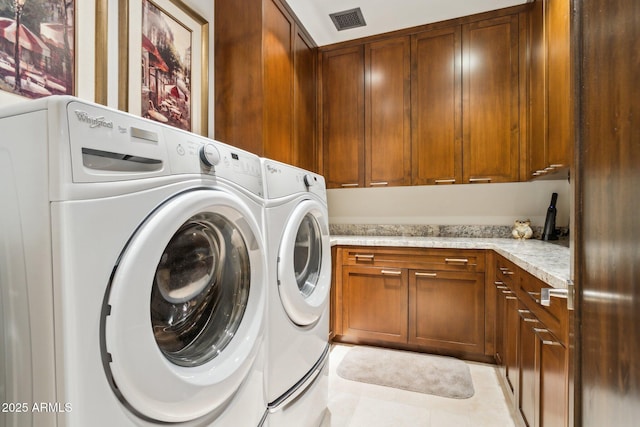 washroom featuring separate washer and dryer, light tile patterned floors, and cabinets