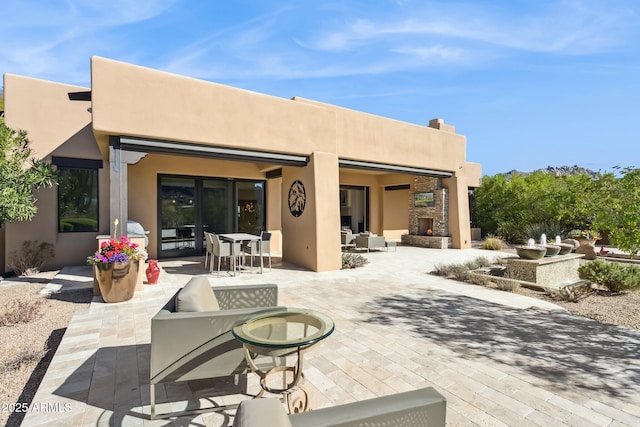 rear view of property with a patio and an outdoor stone fireplace