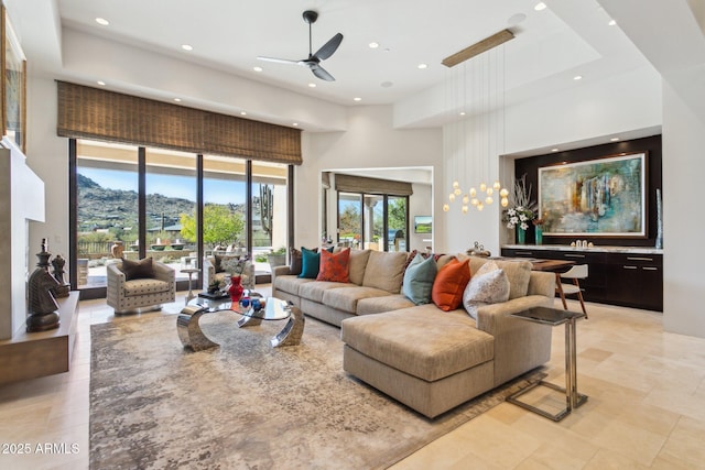 living room with a mountain view, ceiling fan with notable chandelier, and a high ceiling