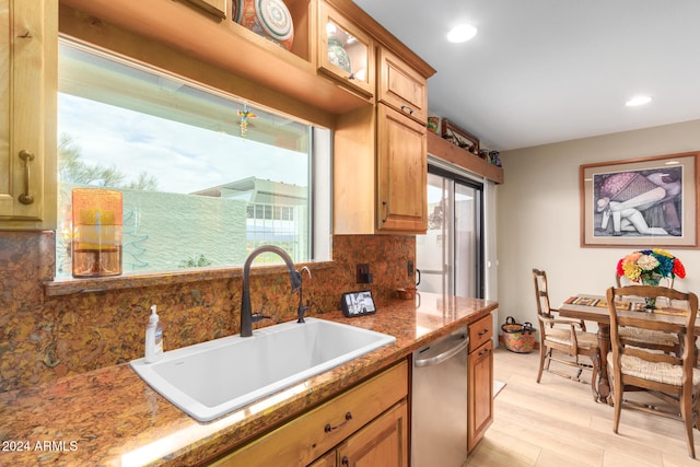 kitchen featuring light hardwood / wood-style floors, sink, tasteful backsplash, dark stone counters, and dishwasher