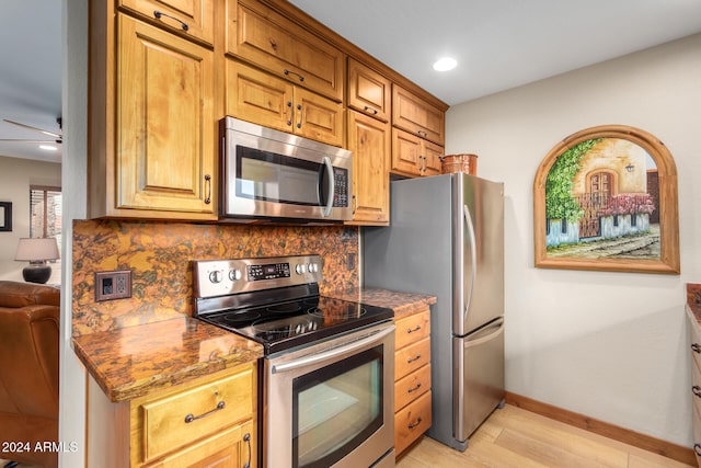 kitchen featuring stainless steel appliances, ceiling fan, backsplash, and light hardwood / wood-style flooring