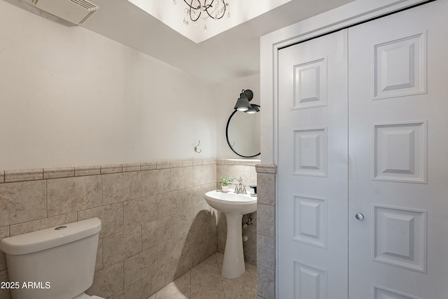 bathroom featuring tile patterned flooring, visible vents, toilet, wainscoting, and tile walls