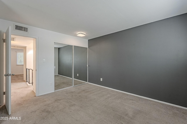 unfurnished bedroom featuring carpet flooring, baseboards, visible vents, and a closet