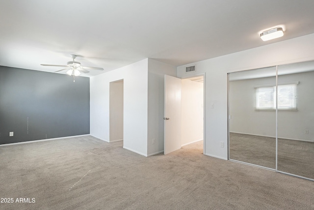 unfurnished bedroom featuring visible vents, a closet, carpet flooring, baseboards, and ceiling fan