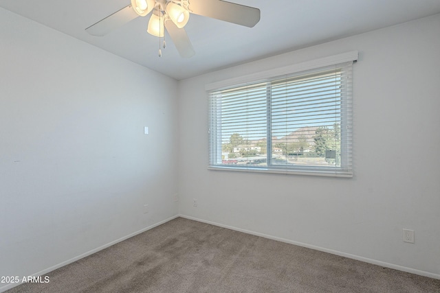 carpeted empty room featuring a ceiling fan and baseboards