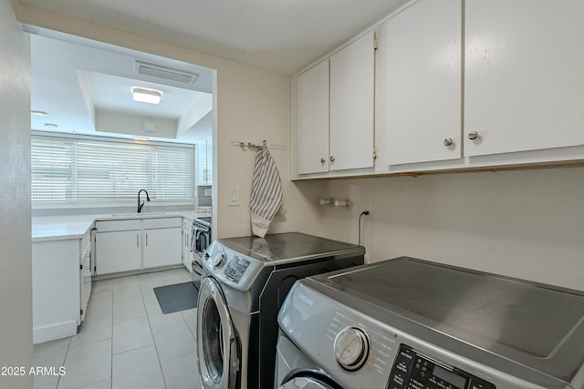 laundry room featuring light tile patterned floors, separate washer and dryer, visible vents, and a sink