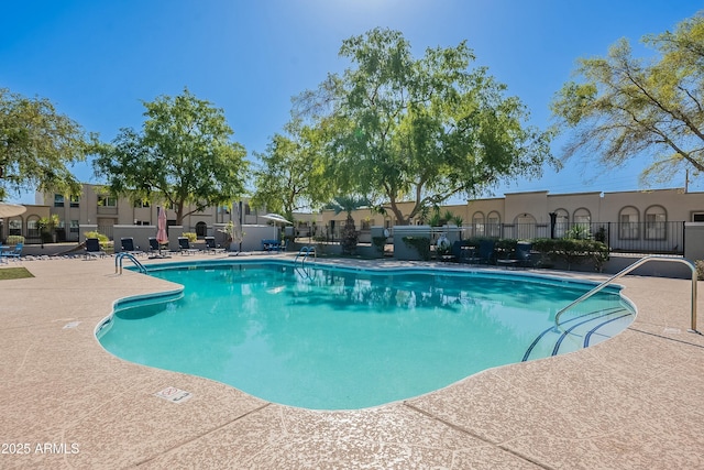 community pool with a patio and fence