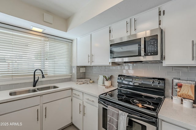 kitchen featuring stainless steel microwave, range with electric cooktop, decorative backsplash, white cabinets, and a sink