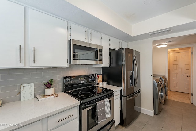 kitchen with visible vents, independent washer and dryer, stainless steel appliances, white cabinets, and light tile patterned floors