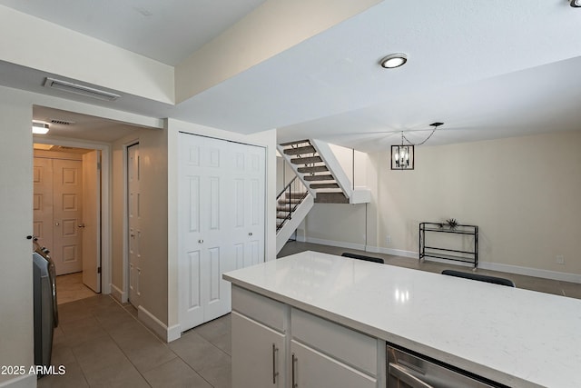 kitchen with baseboards, visible vents, light tile patterned flooring, light countertops, and white cabinetry