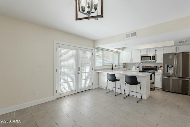 kitchen with a peninsula, tasteful backsplash, visible vents, and appliances with stainless steel finishes