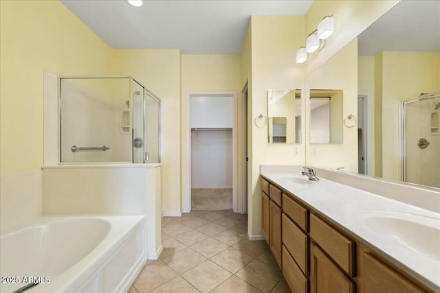 bathroom featuring a bath, a stall shower, a spacious closet, and a sink