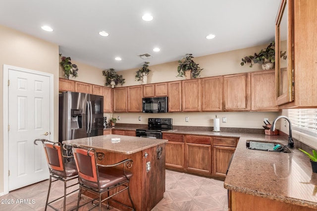 22022 W Moonlight Path, Buckeye, AZ 85326 - kitchen featuring black appliances, a sink, a center island, a breakfast bar area, and stone countertops