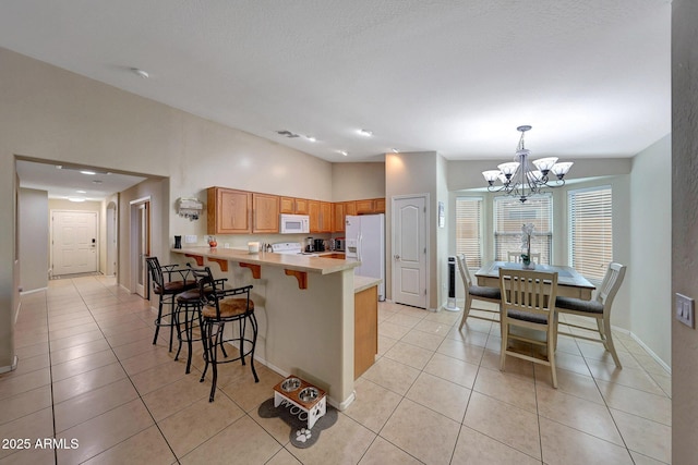 9926 W Gross Ave, Tolleson, AZ 85353 - kitchen with white appliances, a chandelier, a peninsula, light tile patterned floors, and recessed lighting