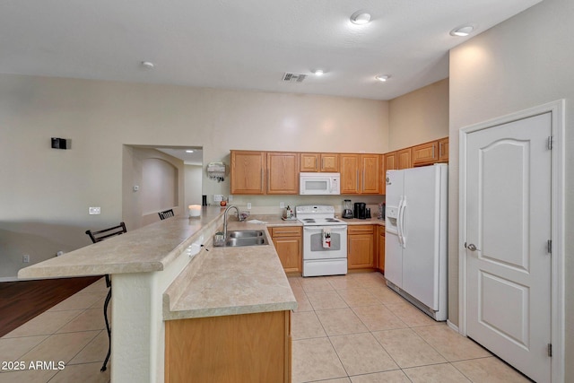 9926 W Gross Ave, Tolleson, AZ 85353 - kitchen featuring white appliances, a peninsula, light tile patterned flooring, light countertops, and a kitchen breakfast bar