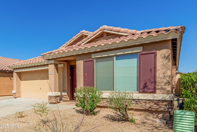 view of front of house with stucco siding, a tile roof, concrete driveway, and a garage