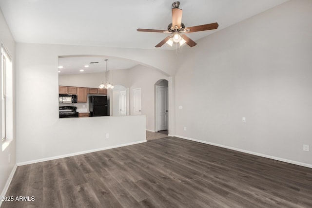 unfurnished living room with arched walkways, dark wood finished floors, lofted ceiling, and ceiling fan with notable chandelier