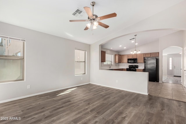 unfurnished living room with wood finished floors, ceiling fan with notable chandelier, arched walkways, baseboards, and lofted ceiling