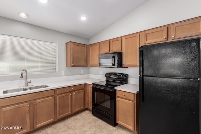 kitchen with a sink, vaulted ceiling, brown cabinetry, light countertops, and black appliances