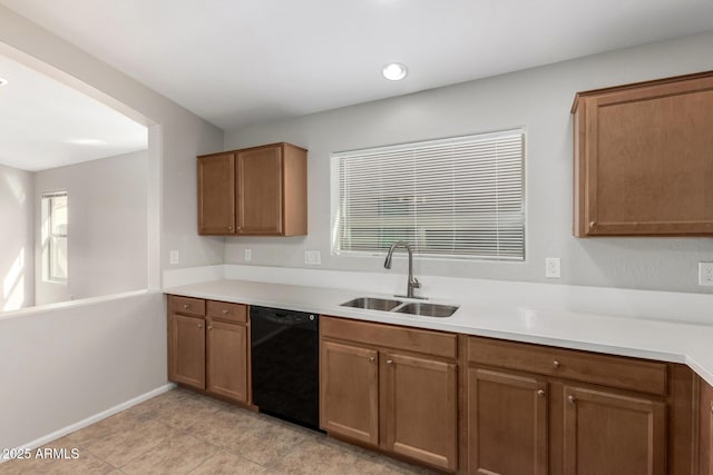 kitchen featuring brown cabinetry, light countertops, a sink, and black dishwasher