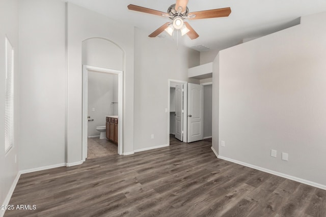 unfurnished bedroom with baseboards, ensuite bath, dark wood-style floors, and visible vents