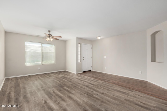 spare room featuring wood finished floors, a ceiling fan, and baseboards