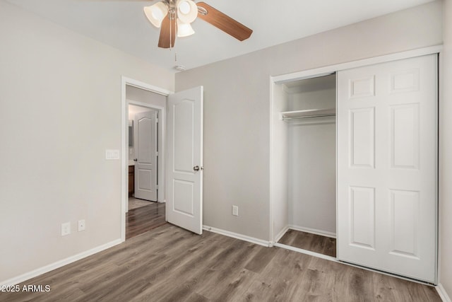 unfurnished bedroom featuring baseboards, a ceiling fan, wood finished floors, and a closet