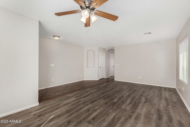 empty room with ceiling fan, arched walkways, and dark wood-type flooring