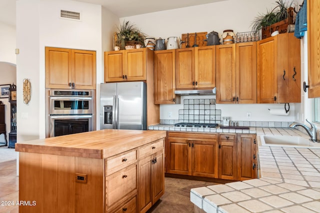 kitchen featuring tile countertops, a center island, stainless steel appliances, and sink