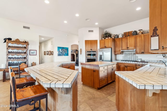 kitchen featuring a kitchen breakfast bar, tile counters, a kitchen island, and stainless steel appliances