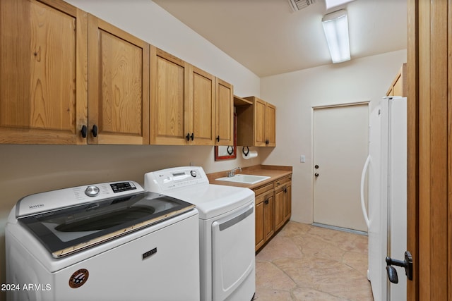 laundry area featuring washing machine and clothes dryer, sink, light tile patterned flooring, and cabinets