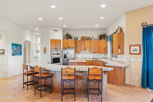 kitchen with appliances with stainless steel finishes, a kitchen breakfast bar, tasteful backsplash, sink, and a kitchen island