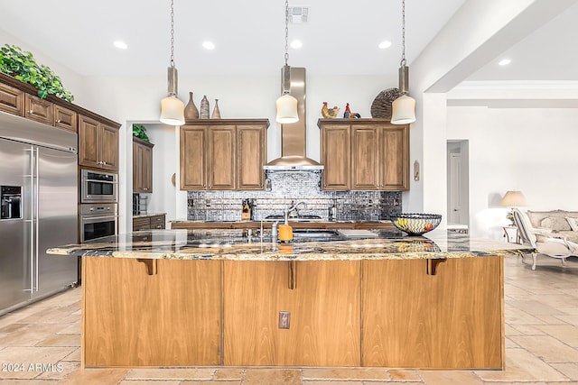 kitchen featuring a breakfast bar, dark stone countertops, decorative light fixtures, and appliances with stainless steel finishes