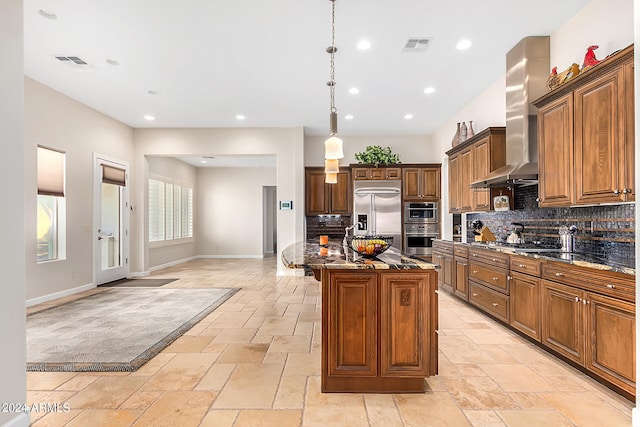 kitchen featuring pendant lighting, dark stone counters, decorative backsplash, appliances with stainless steel finishes, and a center island with sink