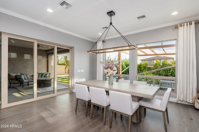 dining room featuring dark wood-type flooring, a wealth of natural light, and ornamental molding