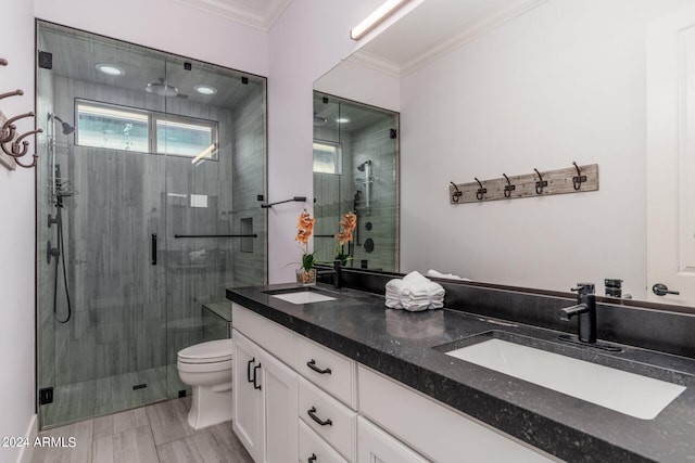 bathroom featuring toilet, vanity, a shower with door, and ornamental molding