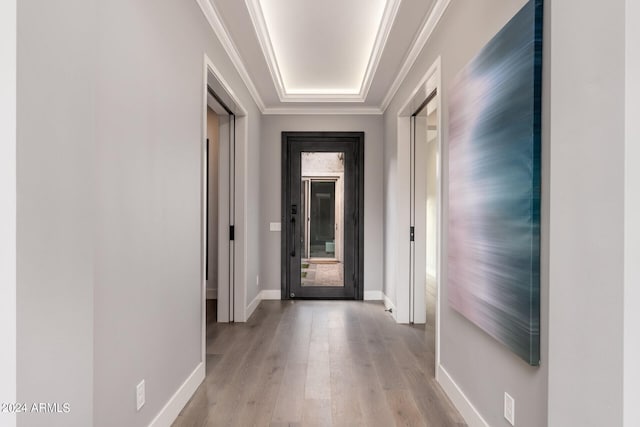 corridor with light hardwood / wood-style floors and ornamental molding