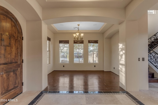 entryway with a tray ceiling, dark hardwood / wood-style flooring, and a notable chandelier