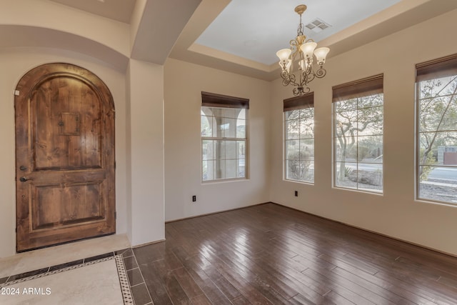 foyer with a tray ceiling, dark hardwood / wood-style flooring, and an inviting chandelier