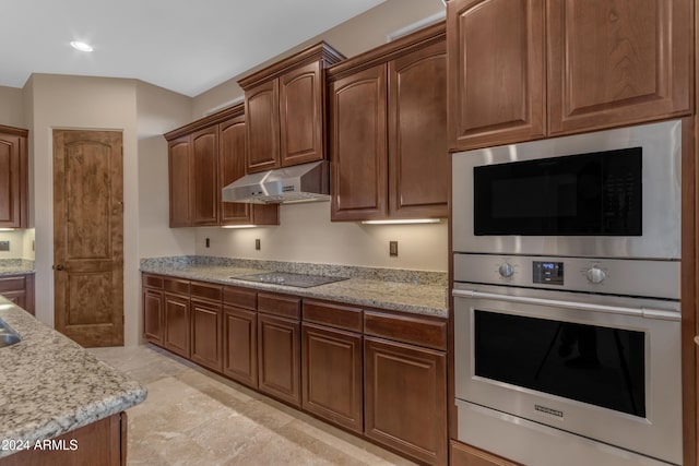 kitchen with light stone countertops, black electric stovetop, double oven, and built in microwave