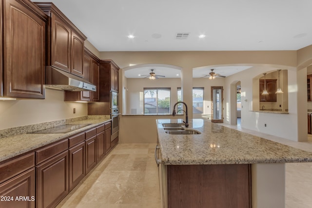 kitchen with black electric stovetop, sink, a kitchen island with sink, and ceiling fan