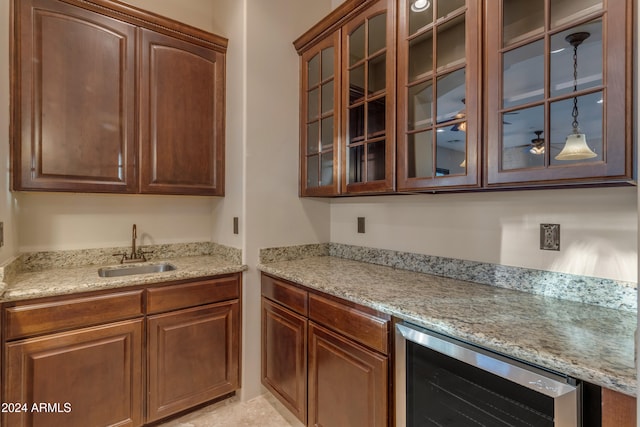 kitchen with light stone counters, beverage cooler, and sink