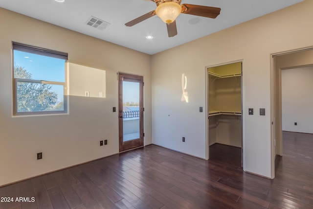 interior space with ceiling fan, dark hardwood / wood-style floors, a walk in closet, and a closet