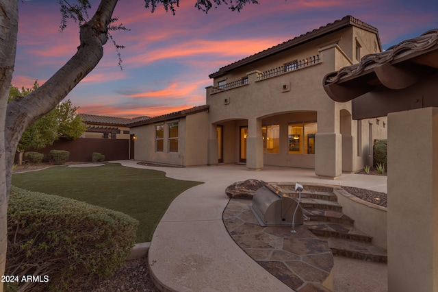 back house at dusk featuring a patio area, a yard, and area for grilling